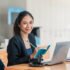 Young Asian businesswoman sitting at their desk and take notes using laptop in the office.